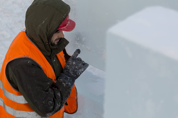 Portret van een assembler-werknemer in een jas met een capuchon lossen ijs platen - Foto, afbeelding