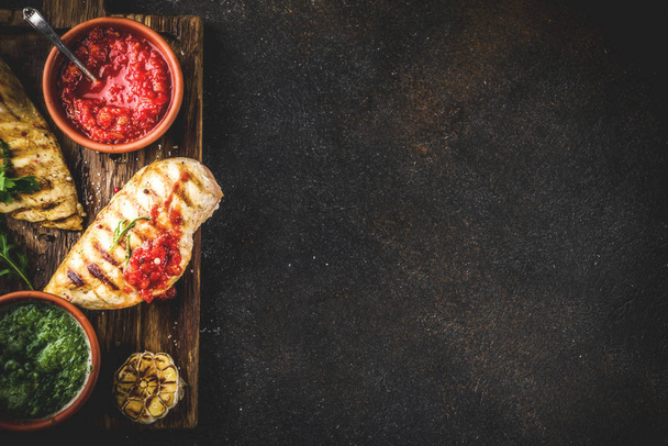 Grillowana pierś z kurczaka z pikantnymi sosami, pomidorów i ziół na ciemnym tle zardzewiały kopia miejsce widok z góry - Zdjęcie, obraz