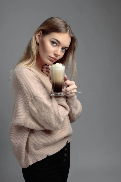 Ír kávé vonzó fiatal nő. Gyönyörű szőke egy pulóvert, gazdaság, egy bögre kávét tejszínnel. - Fotó, kép