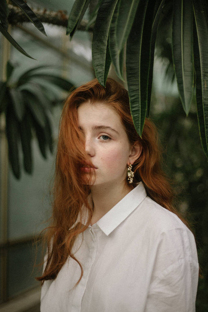 yeşil bitkiler arasında poz beyaz gömlekli şehvetli Kızıl saçlı kadın  - Fotoğraf, Görsel