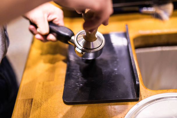Чоловік використовує тампон, щоб пресувати свіжомелену ранкову каву в кавовий планшет
 - Фото, зображення