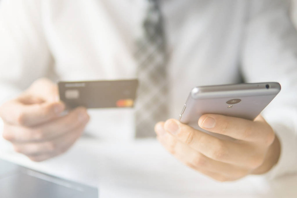 Geschäftsmann nutzt Kreditkarte und Smartphone für Online-Bezahlung. Senden von E-Mail, Handy. weißer Hintergrund. Büroarbeit. Telefon aus nächster Nähe. Online einkaufen. Leichte Lecks - Foto, Bild