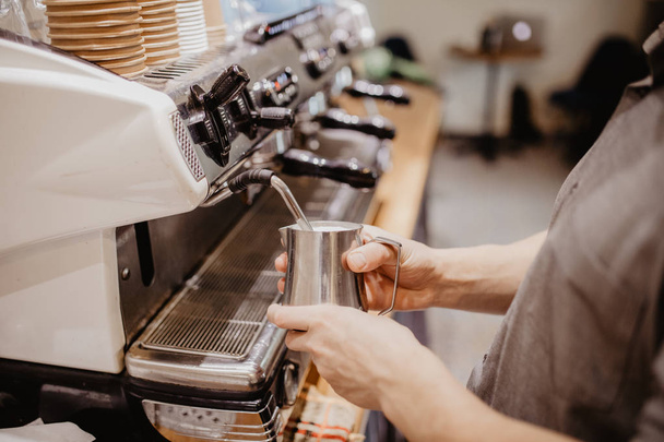 Barista stomen van melk voor warme cappuccino met machine in de winkel van de koffie in de ochtend - Foto, afbeelding
