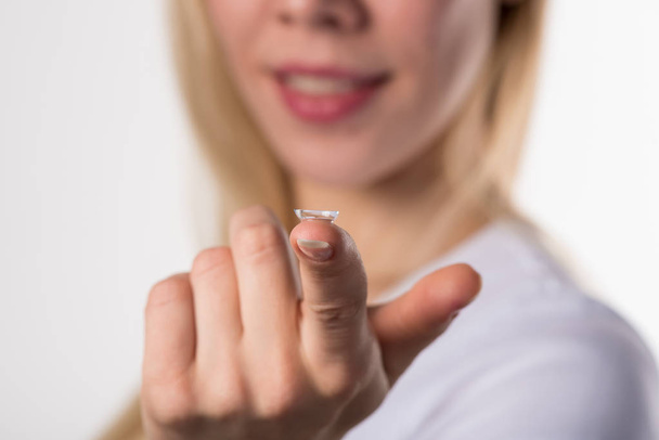 Soft contact lens is lying on the finger of the female hand on a white background - Fotografie, Obrázek
