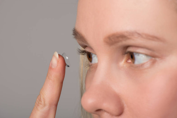 Una chica con hermosos ojos marrones lleva una lente de contacto para la visión
 - Foto, Imagen