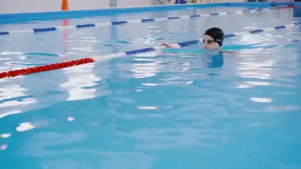 -プールでの子供のためのスイミング レッスン美しい色白の少女は、水に泳ぐ - 映像、動画