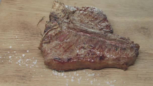 Gewürz wird auf das fertige saftige Steakstück gegossen. Gebratenes Fleisch in Flammen steht auf dem Brett - Filmmaterial, Video