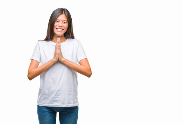 Young asian woman over isolated background praying with hands together asking for forgiveness smiling confident. - Photo, image
