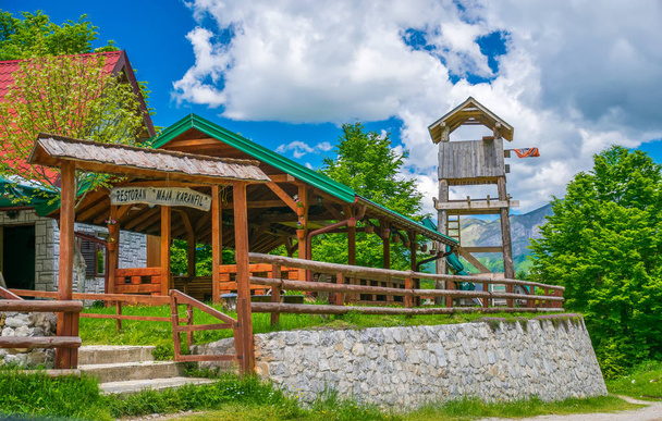 Μαυροβούνιο, βουνά αυτό - 29 Μαΐου 2017: Τουρίστες επισκέφθηκαν εστιατόριο που βρίσκεται στον κάμπο μεταξύ ψηλά χιονισμένα βουνά - Φωτογραφία, εικόνα