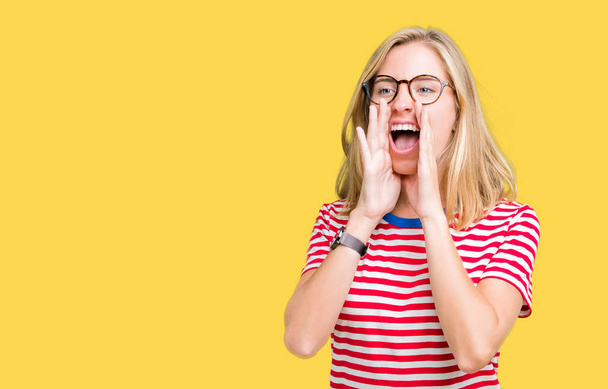 Krásná mladá žena nosí brýle izolované pozadí křičí nahlas zlobí ruce ústa - Fotografie, Obrázek