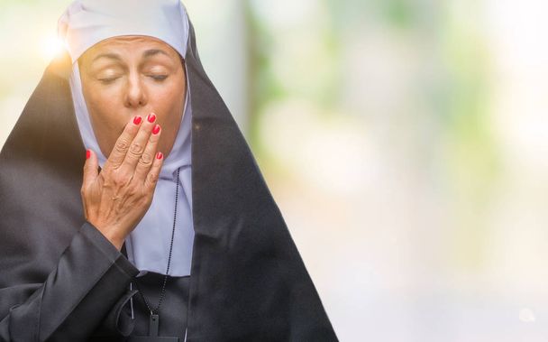 Orta yaş üst düzey Hıristiyan Katolik Rahibe kadın izole arka plan üzerinde el ile ağız kapsayan yorgun esneme sıkılmış. Restless ve uyku hali. - Fotoğraf, Görsel
