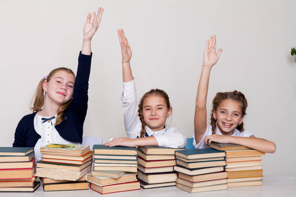 tres colegialas en clase en el escritorio con libros mano a mano para responder
 - Foto, imagen