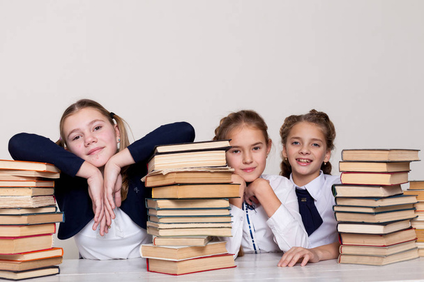 tres niñas colegialas en un escritorio con libros sobre la lección en la escuela
 - Foto, imagen