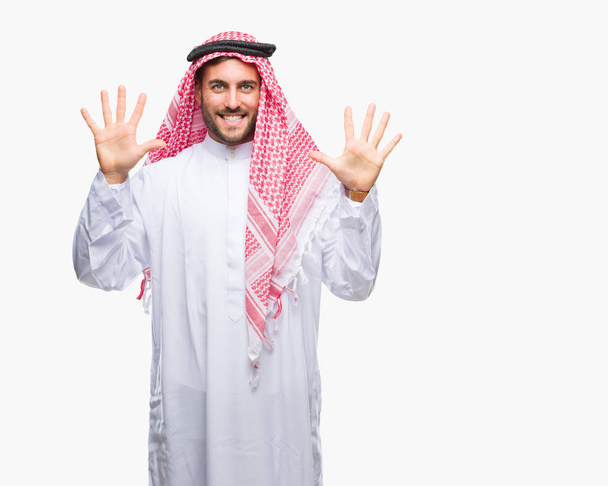 Όμορφος νεαρός φορώντας keffiyeh απομονωμένη φόντο και στραμμένο προς τα επάνω με τα δάχτυλά σας αριθμός δέκα χαμογελώντας αυτοπεποίθηση και χαρούμενοι. - Φωτογραφία, εικόνα