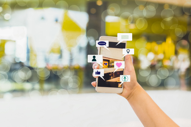 Woman hand hold Smartphone share social media, with  blurred backgrounds department stores and bokeh, concept  lifestyle and online wireless networks. - Photo, Image
