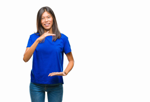 Młoda Azjatka kobieta na białym tle gestykulacji z rąk Wyświetlono duże i duży rozmiar znak, symbol środka. Uśmiecha się, patrząc na kamery. Koncepcji pomiaru. - Zdjęcie, obraz