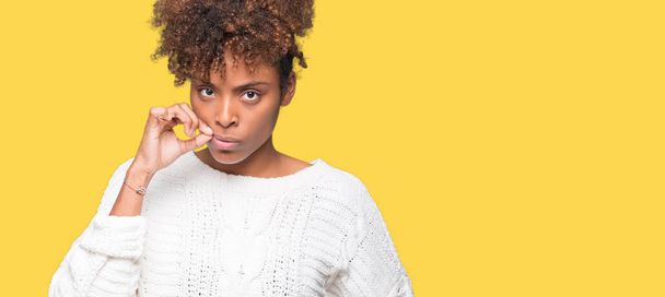 Όμορφη νεαρή αφρικανική αμερικανική γυναίκα, φορώντας χειμώνα πουλόβερ πάνω από απομονωμένες φόντο το στόμα και τα χείλη κλειστά ως zip με τα δάχτυλα. Μυστική και αθόρυβη, ταμπού μιλάμε - Φωτογραφία, εικόνα