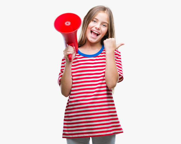 Young beautiful girl yelling through megaphone over isolated background pointing and showing with thumb up to the side with happy face smiling - Φωτογραφία, εικόνα