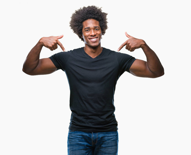 Afroamerikanischer Mann mit isoliertem Hintergrund sieht selbstbewusst aus, mit einem Lächeln im Gesicht, und zeigt mit den Fingern stolz und glücklich. - Foto, Bild