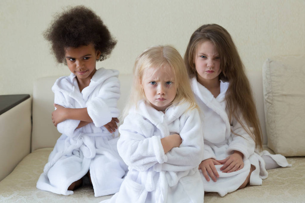 Mujeres enojadas y enojadas con batas blancas. Tres niñas de diferentes nacionalidades se ofenden por sus padres
. - Foto, Imagen