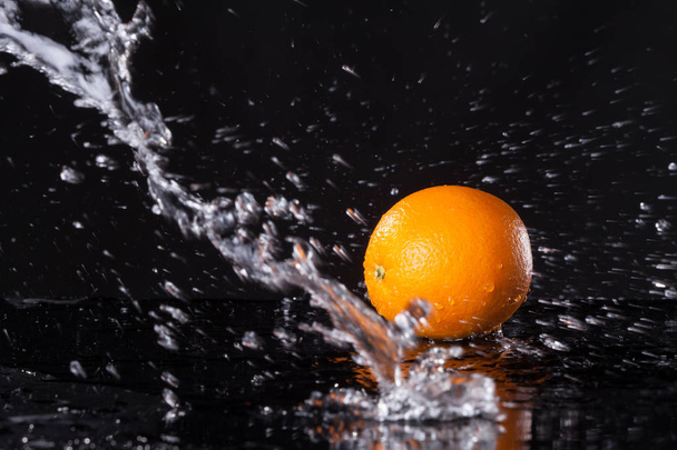 Čerstvý pomeranč na černém pozadí s datovými proudy vody na něm - Fotografie, Obrázek