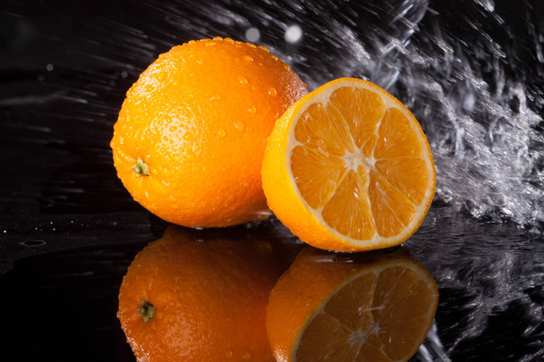 Čerstvý pomeranč na černém pozadí s datovými proudy vody na něm - Fotografie, Obrázek