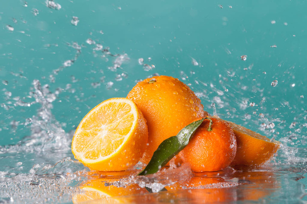 Oranssi viipaleet ja mandariini yli vesi roiske sininen tausta
 - Valokuva, kuva