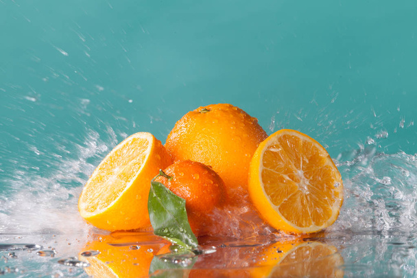Plátky pomeranče a mandarinka vody splash modré pozadí - Fotografie, Obrázek