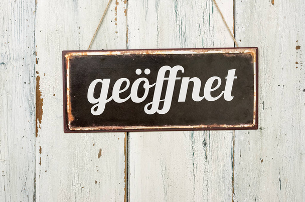 Παλιά μεταλλική πινακίδα μπροστά από ένα λευκό ξύλινο τοίχο - γερμανική λέξη για το άνοιγμα - geoeffnet - Φωτογραφία, εικόνα