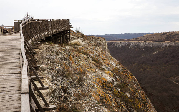 Een oude houten brug in een stenen fort door middel van een afgrond in de bergen. Een houten brug verbindt twee rotsen van een oude Bulgaarse Fort - Foto, afbeelding