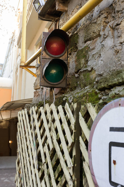 old rusty fence with road sign and traffic lights in old city - Photo, Image