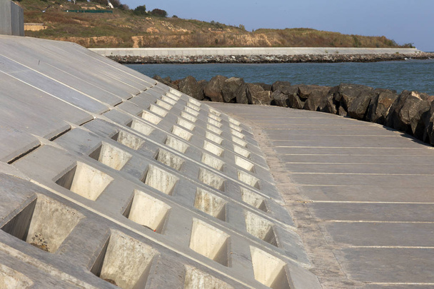 Modern dalgakıran tasarımı ile büyük taş ve beton döşeme özel dalga kıran tasarım hücrelerle Close-up. İskele beton ve taş bloklarla sahil korumaya. Shore konsolidasyon - Fotoğraf, Görsel