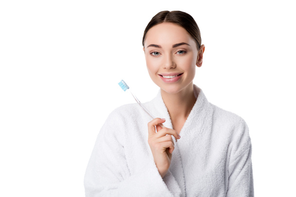 piękna kobieta uśmiechający się w biały szlafrok trzymając szczoteczkę do zębów, na białym tle - Zdjęcie, obraz