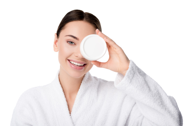 beautiful woman in bathrobe holding moisturizing cream in front of face isolated on white - Foto, afbeelding