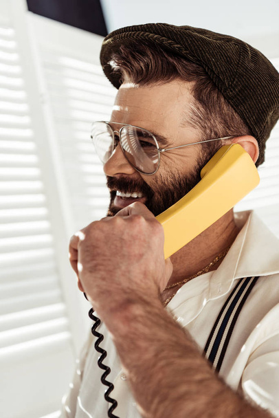 ビンテージの電話で話しているひげを生やした男の笑みを浮かべてください。 - 写真・画像