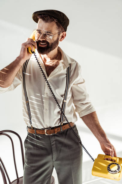 красивий бородатий чоловік посміхається і говорить на ретро телефоні
 - Фото, зображення