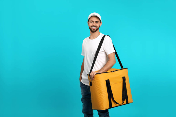 Young courier with thermo bag on color background, space for text. Food delivery service - Φωτογραφία, εικόνα