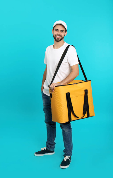 Young courier with thermo bag on color background. Food delivery service - Foto, Imagen