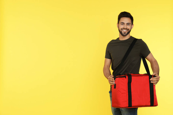 Young courier with thermo bag on color background, space for text. Food delivery service - Zdjęcie, obraz