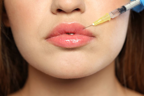 Jonge vrouw krijgen lippen injectie, close-up. Cosmetische chirurgie - Foto, afbeelding