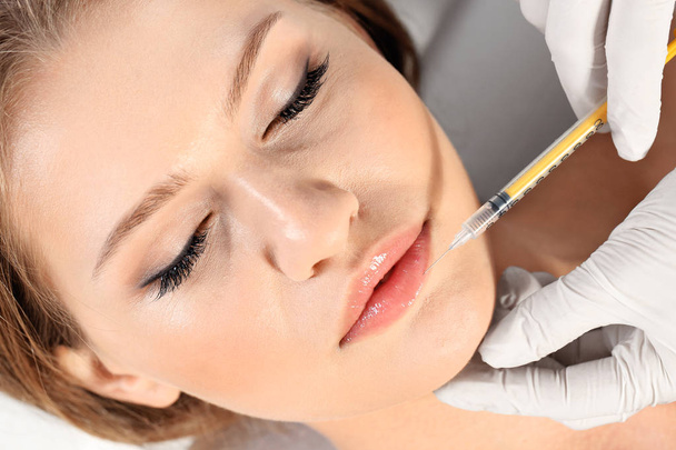 Young woman getting lips injection in clinic, closeup. Cosmetic surgery - Foto, Bild