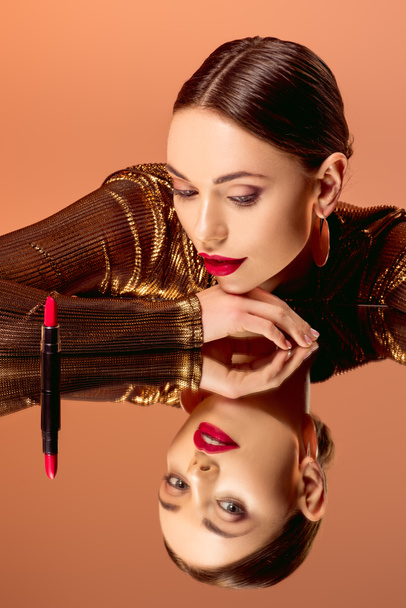 attractive woman with glamorous makeup, mirror reflection and red lipstick posing isolated on orange - Φωτογραφία, εικόνα