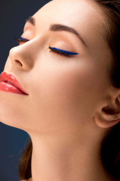 selective focus of beautiful woman with glamorous makeup and eyes closed isolated on blue - Foto, Imagem