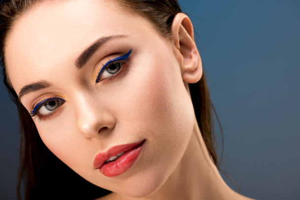 portrait of beautiful woman with glamorous makeup looking at camera isolated on blue - Fotó, kép