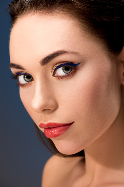 selective focus of beautiful woman with glamorous makeup looking at camera isolated on blue - Foto, afbeelding
