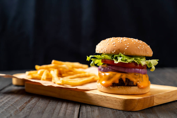 fresh tasty beef burger with cheese and french fries on wood background - Fotoğraf, Görsel