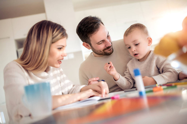 Mother and father drawing together with their child at home. - Photo, Image