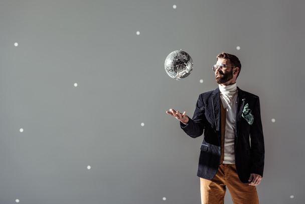 jóképű férfi szemüveg hányt disco labdát a szürke háttér - Fotó, kép
