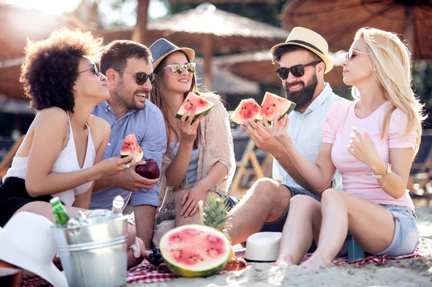 Friends having great time on the beach,eating watermelon. - Foto, imagen