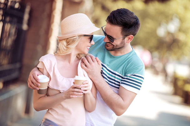 Веселая молодая пара пьет кофе, чтобы пойти и весело провести время на улице
. - Фото, изображение